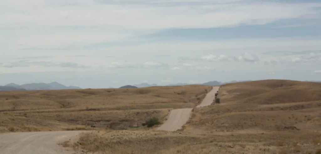 Verlassene Straße in Wüstenlandschaft mit hügeligem Hintergrund